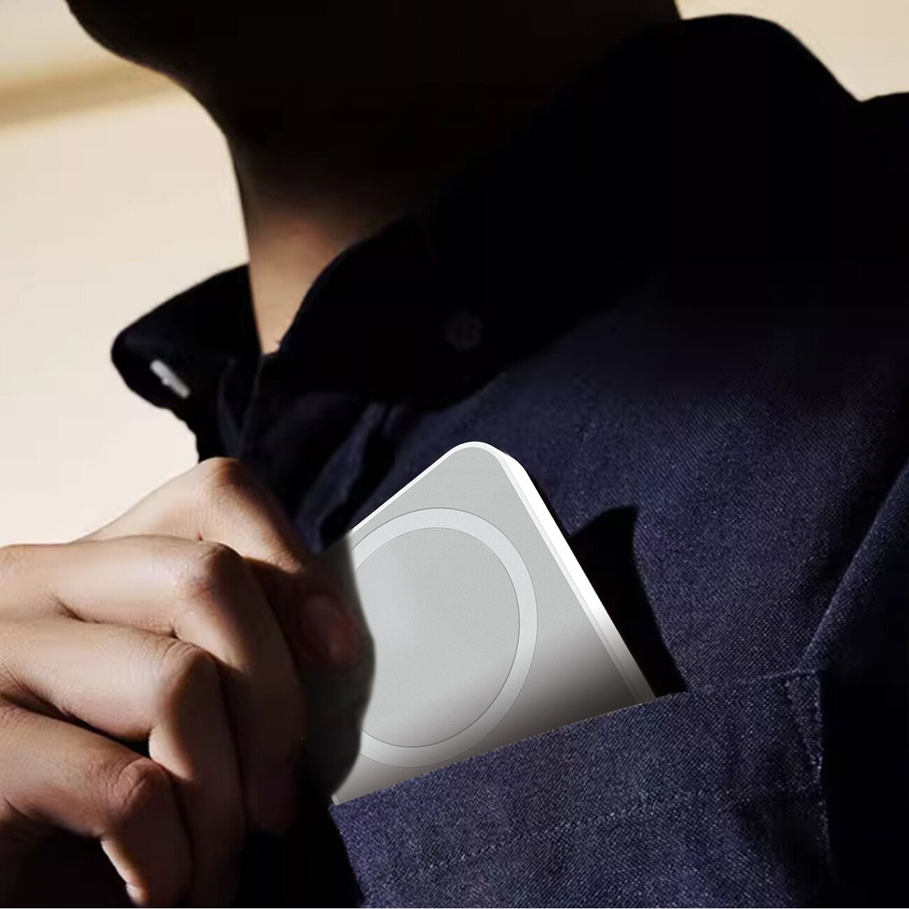 Osoba wkłada biały powerbank do kieszeni ciemnej koszuli. Powerbank ma okrągły wzór na powierzchni.