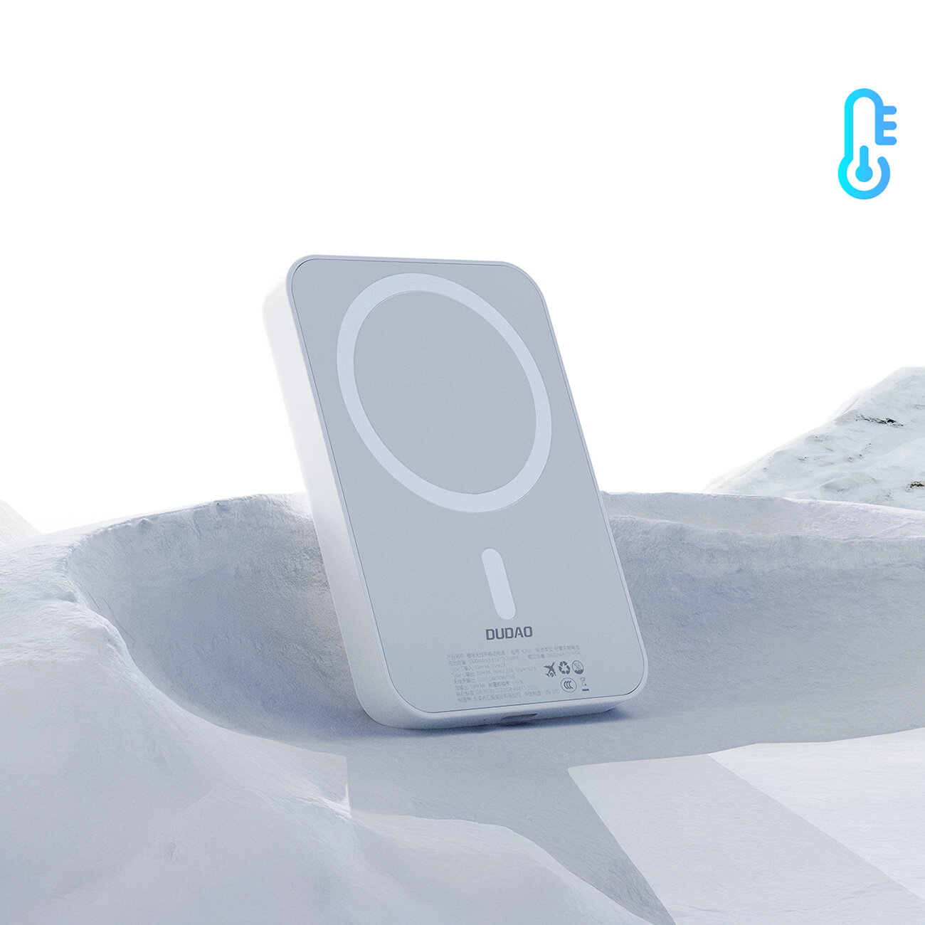 Biały powerbank z logo \'DUDAO\' stoi na jasnym tle przypominającym śnieg. W prawym górnym rogu widoczna jest niebieska ikona termometru.