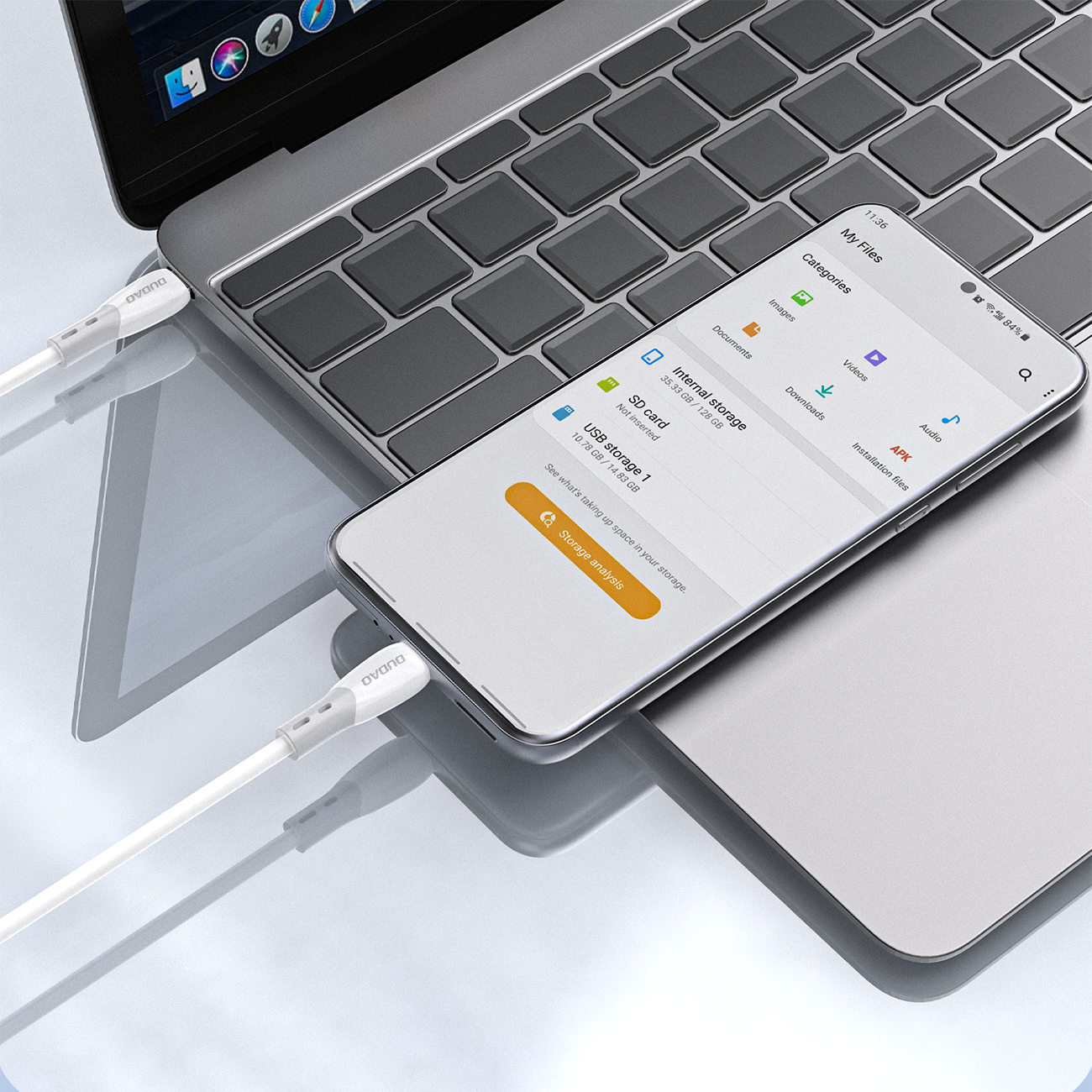 Na obrazie widać biały kabel USB-C podłączony do laptopa i smartfona, na którym wyświetlana jest aplikacja \'My Files\'. Na kablu widoczne jest logo \'Dudao\'.