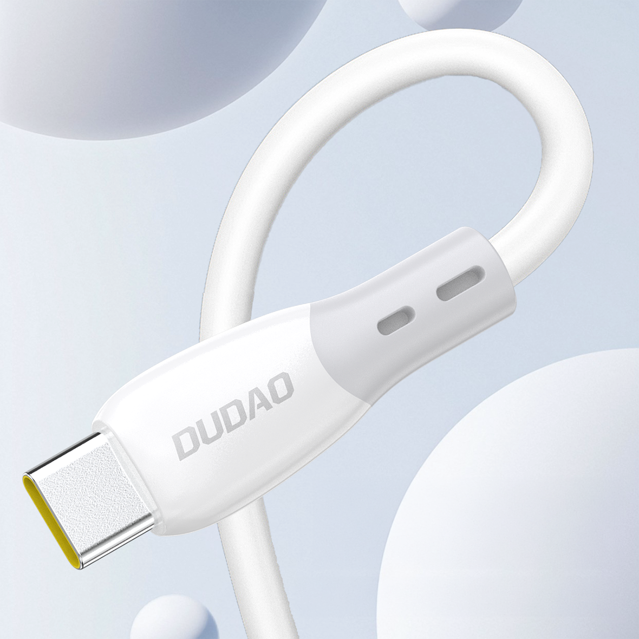 Biały kabel USB-C z silikonowym oplotem, z widocznym logo \'DUDAO\' na złączu. Tło jest jasne z rozmytymi, okrągłymi kształtami.