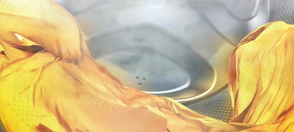 PRALKA WHIRLPOOL TDLR 65230S PL/N Zdjęcie ukazuje fragment bębna pralki z delikatnie opadającą tkaniną w ciepłym, żółtym odcieniu. Ujęcie podkreśla miękkość materiału oraz spokojny przebieg cyklu prania FreshCare świeżość prania cyrkulacja powietrza ochrona tkanin zagniecenia