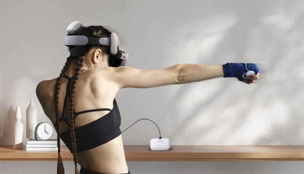 Osoba w goglach VR stoi przed półką, na której znajduje się biały akumulator z napisem \'BOBOVR\'.