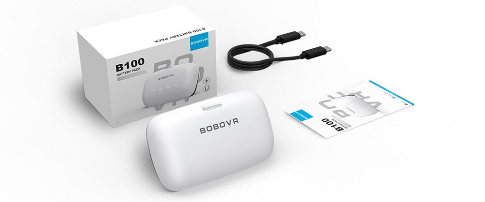 Na obrazie widoczny jest biały akumulator z napisem \'BOBOVR\', pudełko z napisem \'B100 BATTERY PACK\', czarny kabel oraz instrukcja obsługi. Wszystkie elementy są umieszczone na białym tle.