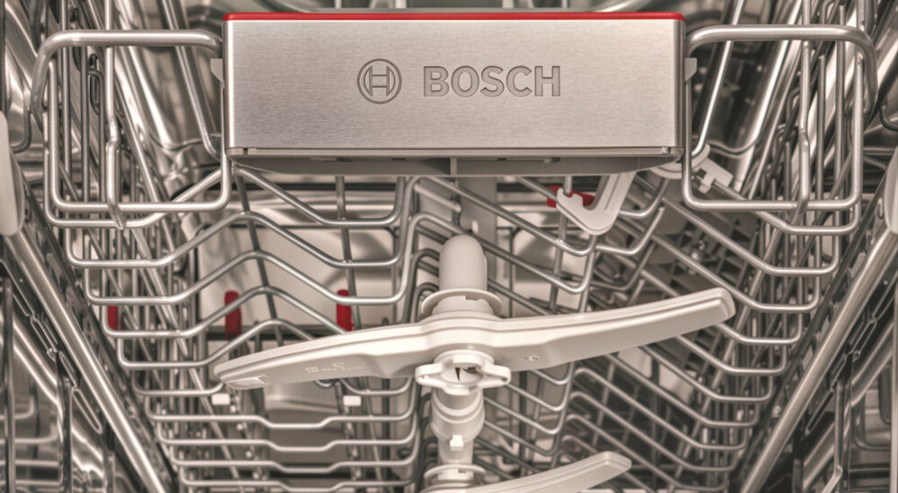 ZMYWARKA BOSCH SPS2HMI02E Wnętrze zmywarki Bosch z widocznymi ramionami spryskującymi i metalowymi koszami na naczynia. W górnej części znajduje się element z logo „BOSCH” oraz czerwonym akcentem DuoPower dwa ramiona zraszające precyzyjna cyrkulacja wody skuteczne usuwanie zabrudzeń ochrona delikatnych naczyń