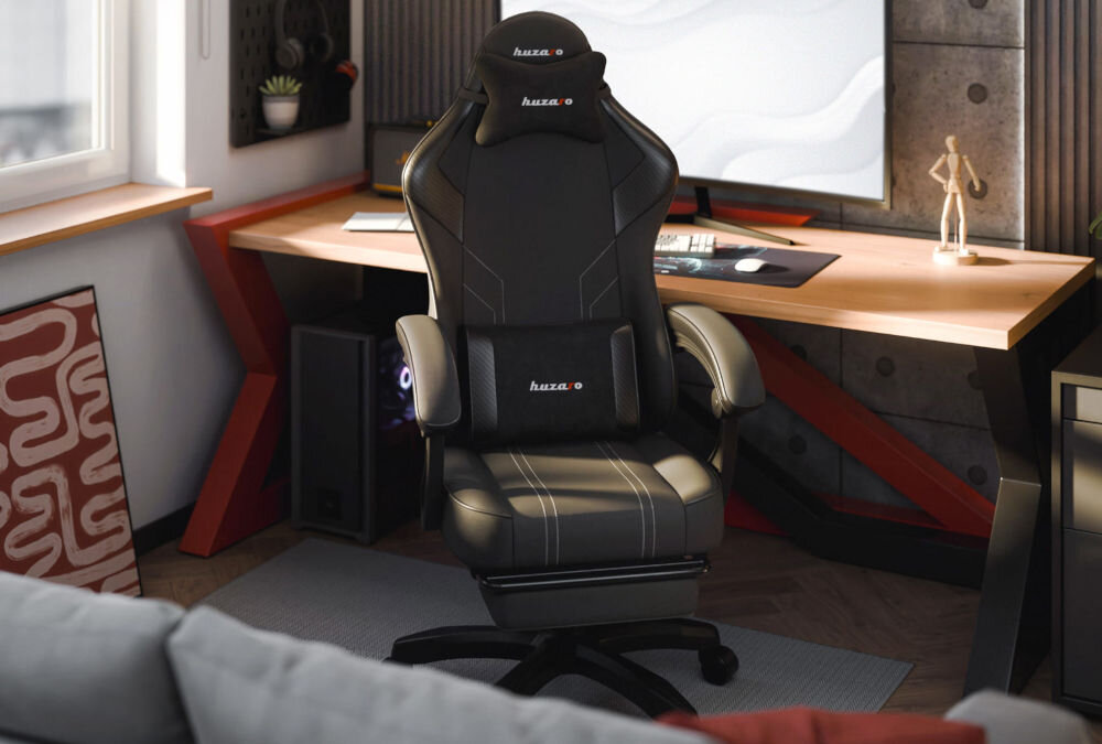 Fotel HUZARO Force 3.7 Czarny prezentacja fotela od przodu w pokoju przy biurku na biurku duży monitor szara kanapa przed fotelem
