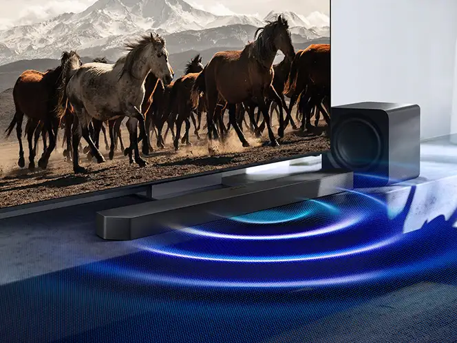 Telewizor z biegnącymi końmi, soundbar Samsung HW-Q990H i subwoofer z niebieskimi falami dźwięku na podłodze.