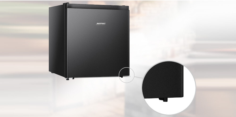 Czarna lodówka z logo \'MPM\' na drzwiach, przedstawiona na rozmytym tle. Obok znajduje się powiększenie dolnej części lodówki.