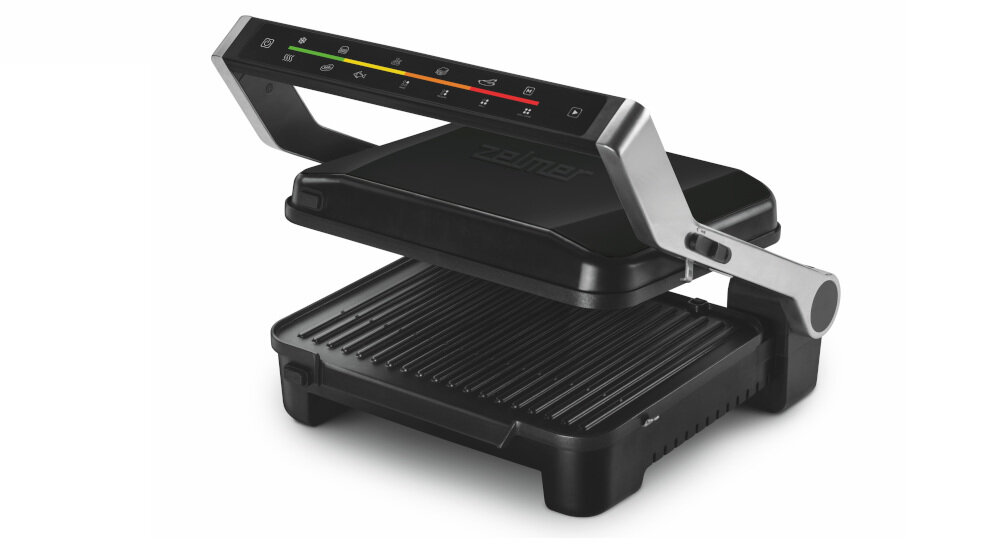 Grill elektryczny z czarną obudową i srebrnymi uchwytami, posiada panel sterowania z kolorowymi ikonami. Na górnej części widoczne jest logo \'Zelmer\'.