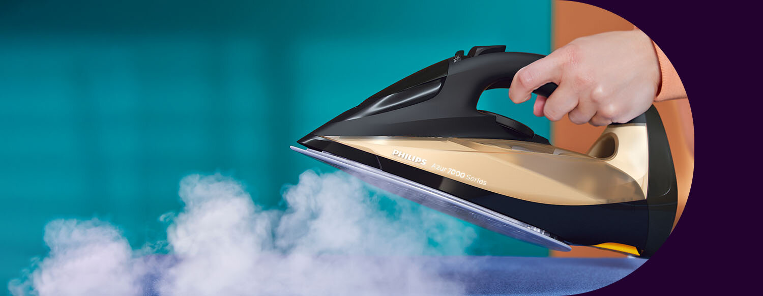 Osoba trzyma żelazko, z którego wydobywa się para. Na żelazku widoczny jest napis \'PHILIPS Azur 7000 Series\'.