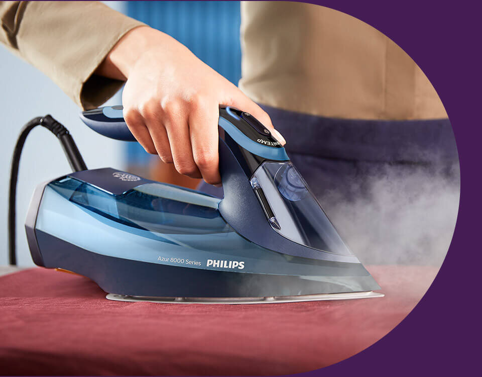 Osoba prasuje tkaninę żelazkiem marki PHILIPS, model Azur 8000 Series. Żelazko emituje parę, a na jego obudowie widoczny jest napis \'PHILIPS Azur 8000 Series\'.