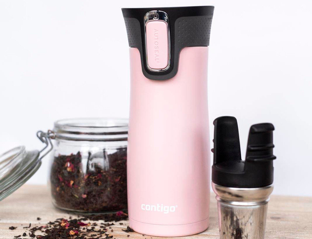 Różowy kubek termiczny z czarnym wieczkiem i napisem \'contigo\' na dole. Obok znajduje się słoik z herbatą i metalowy zaparzacz.
