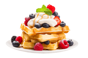 Stos gofrów na talerzu, udekorowany bitą śmietaną, malinami, jagodami i listkiem mięty.