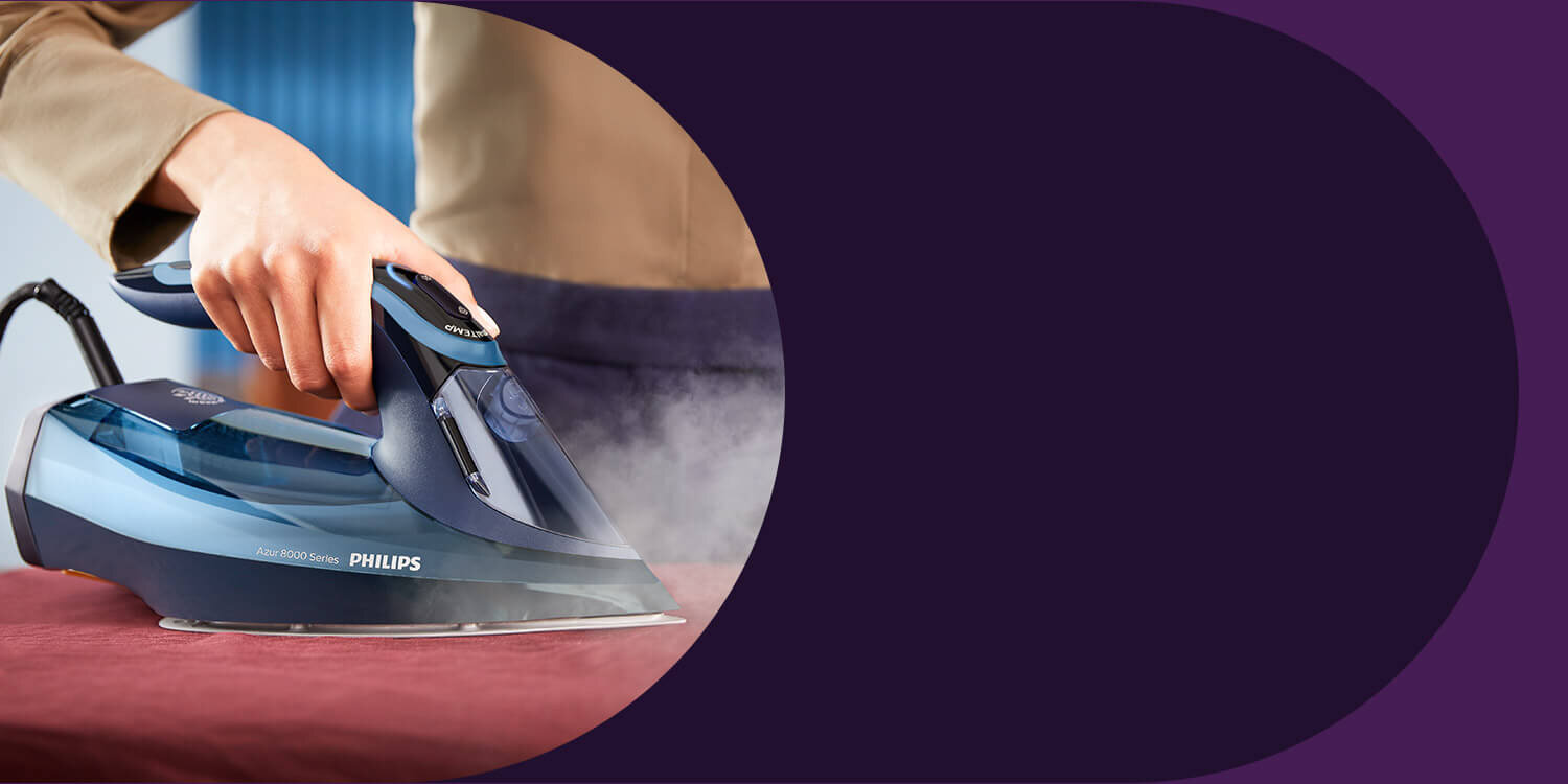 Osoba prasuje tkaninę za pomocą żelazka marki PHILIPS, model Azur 8000 Series. Żelazko emituje parę podczas prasowania.
