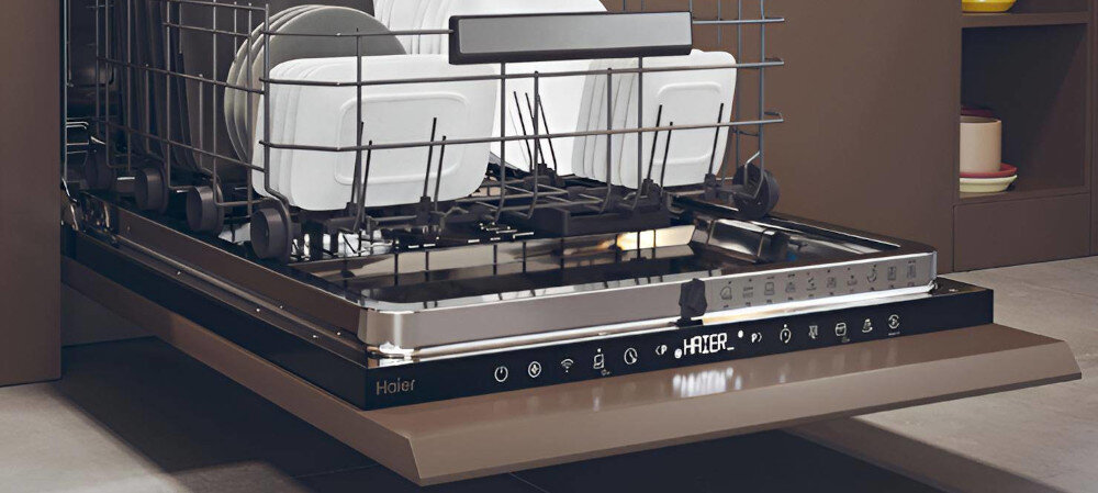 Otwarta zmywarka z widocznymi naczyniami w środku, na panelu sterowania widoczne jest logo \'Haier\'.