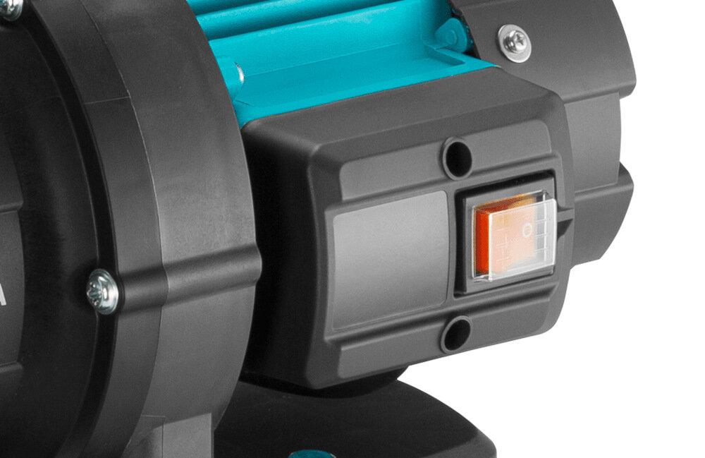 Zbliżenie na część urządzenia z czarną obudową i pomarańczowym przełącznikiem z oznaczeniami \'I\' i \'O\'. Widoczny jest również niebieski element konstrukcji.