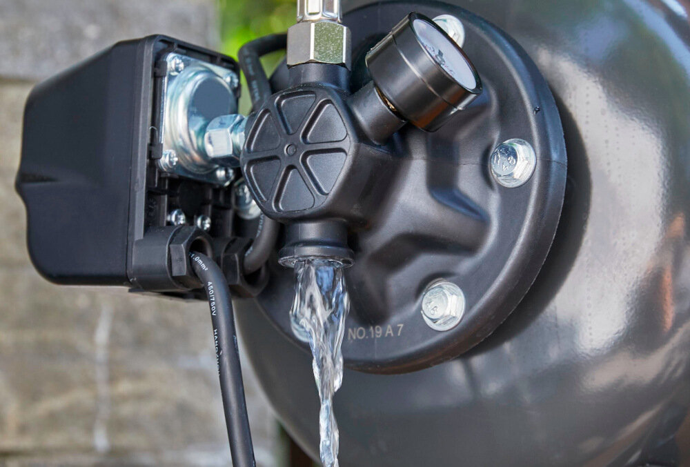 Zbliżenie na część hydroforu z widocznym przepływem wody przez zawór. Na metalowej powierzchni widoczny jest napis \'NO.19 A 7\'.