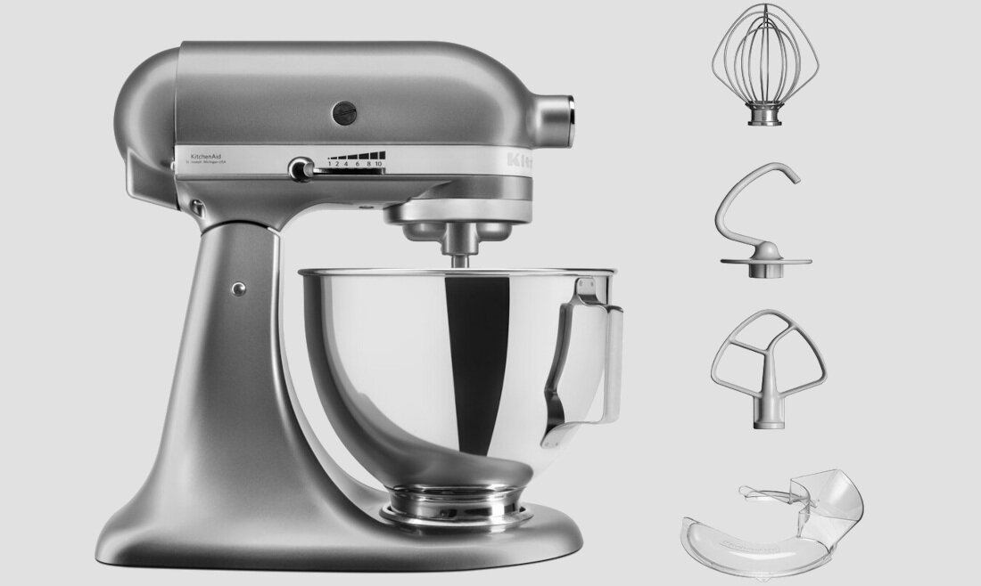 Srebrny robot kuchenny z misą ze stali nierdzewnej, obok widoczne są trzy końcówki: trzepaczka, hak do ciasta i mieszadło, oraz osłona na misę.