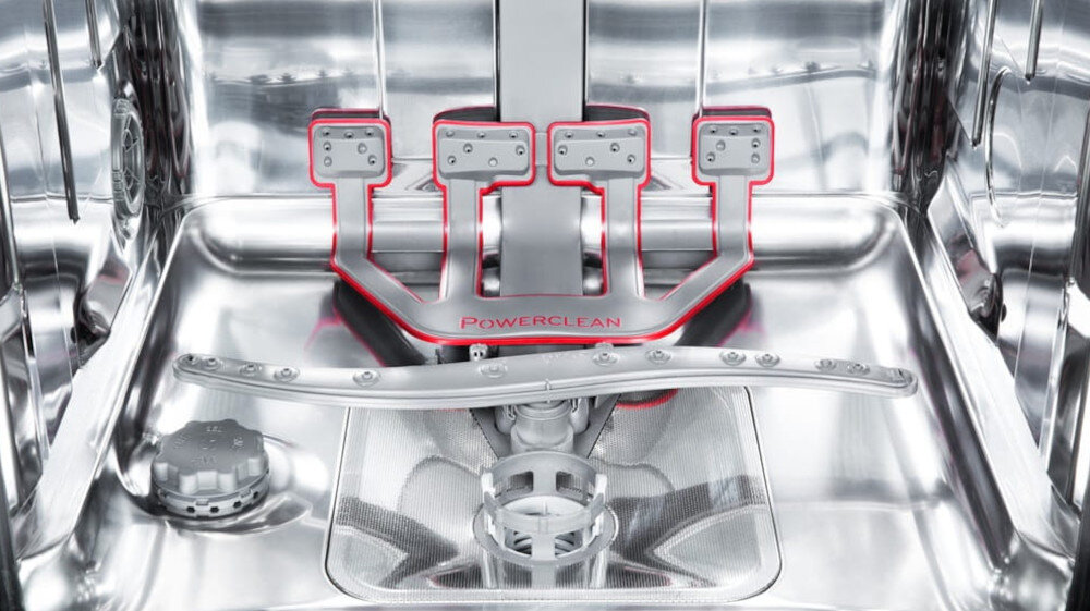 Wnętrze zmywarki z widocznym systemem PowerClean, oznaczonym napisem \'PowerClean\'. W środku znajduje się metalowe ramię spryskujące oraz elementy konstrukcyjne w kolorze srebrnym i czerwonym.