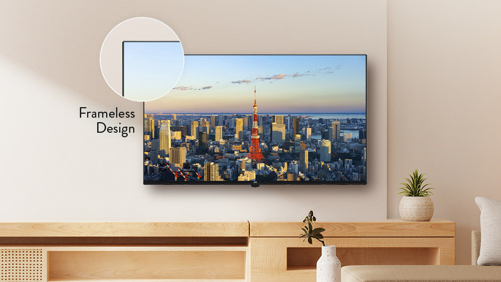Telewizor z wąską ramką wyświetla panoramę miasta z wieżą telewizyjną o zachodzie słońca. Obok ekranu znajduje się napis \'Frameless Design\'.