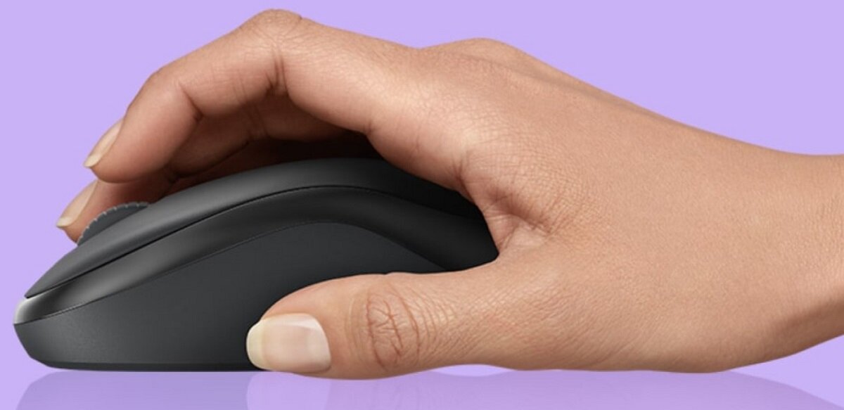Dłoń trzymająca czarną mysz komputerową na fioletowym tle. Mysz ma prosty, ergonomiczny kształt.