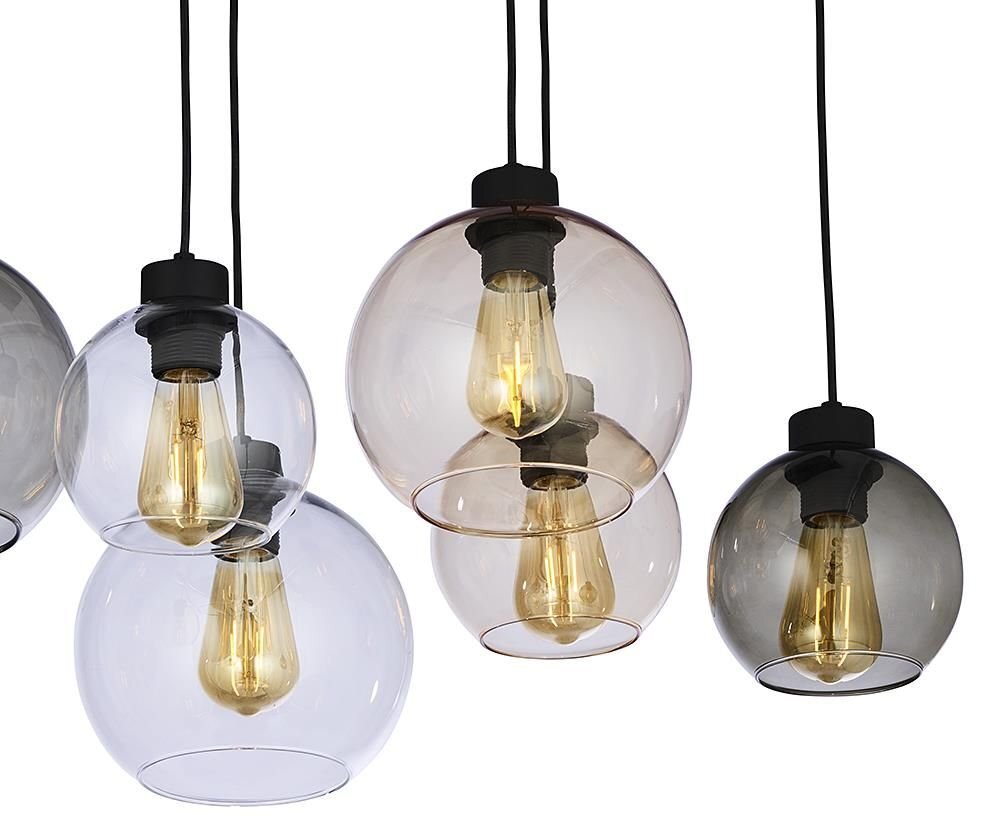 Na obrazie widoczne są szklane klosze lamp wiszących w różnych odcieniach, z widocznymi żarówkami wewnątrz. Klosze mają kulisty kształt i są zawieszone na czarnych przewodach.