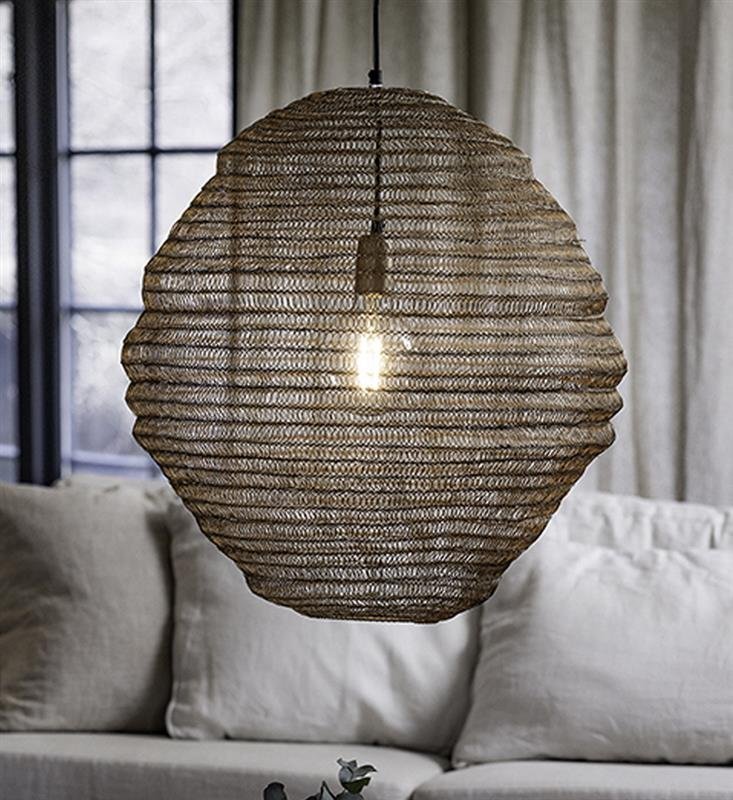Na obrazie widoczna jest wisząca lampa z plecionym kloszem, przez który prześwituje żarówka. W tle znajdują się zasłony i fragment kanapy.