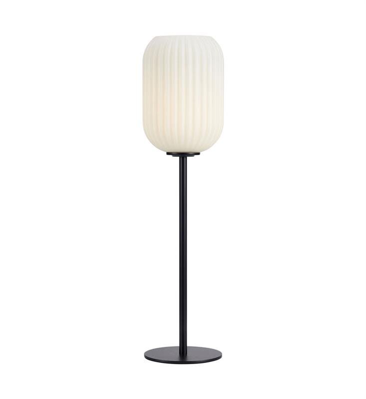 Lampa stołowa z białym, żebrowanym kloszem i czarną, smukłą podstawą na okrągłej stopce.