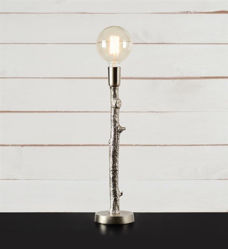 Lampa stołowa o wyglądzie gałęzi z okrągłą żarówką na szczycie, ustawiona na ciemnej powierzchni przed jasnym, drewnianym tłem.