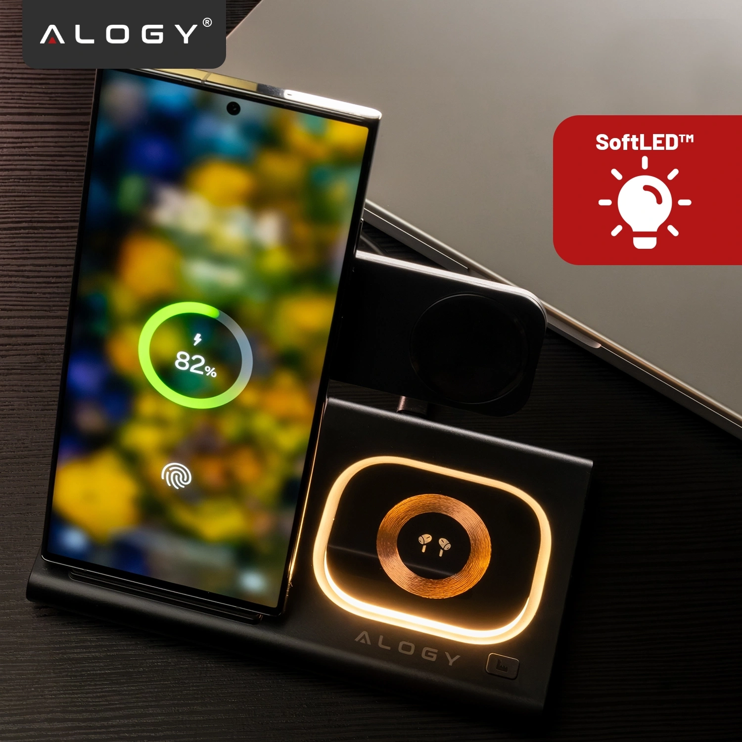 Na obrazie znajduje się czarna ładowarka indukcyjna z miejscem na telefon, zegarek i słuchawki, z logo \'ALOGY\'. Obok widoczny jest czerwony symbol z napisem \'SoftLED™\'.