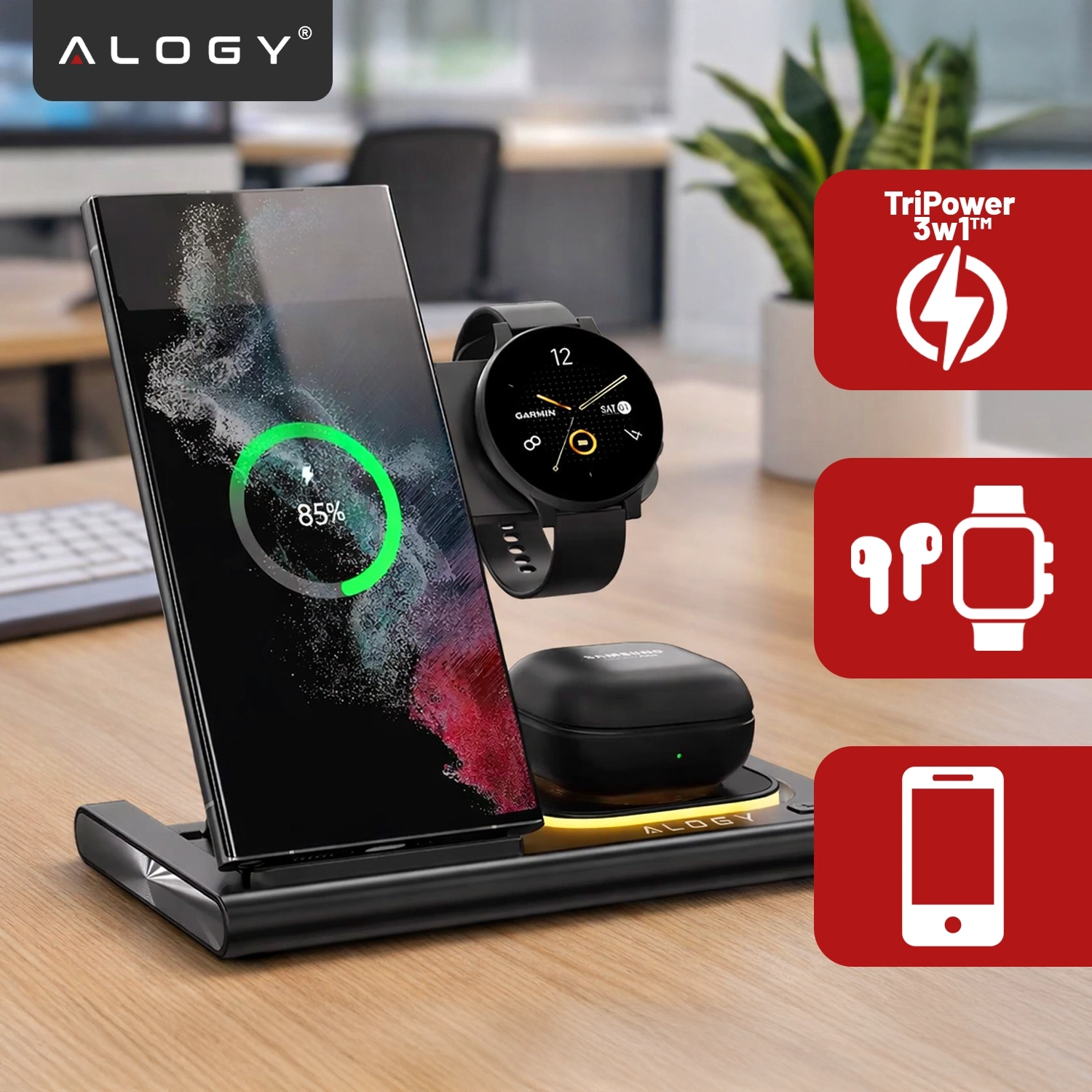 Na obrazie znajduje się czarna ładowarka indukcyjna 3w1 z telefonem, zegarkiem i słuchawkami na biurku. Widoczne są również ikony z napisami: \'TriPower 3w1™\' oraz logo \'ALOGY\'.