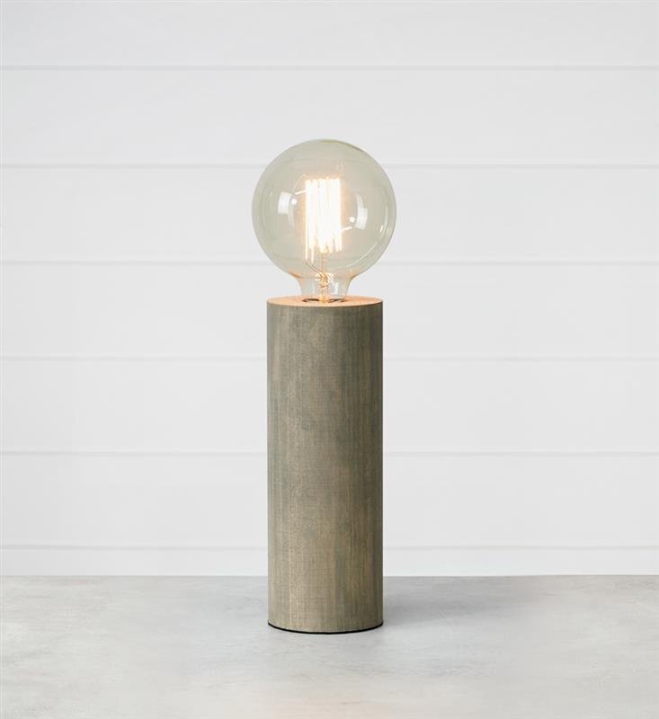 Lampa stołowa z przezroczystą żarówką na cylindrycznej podstawie, ustawiona na jasnym tle.