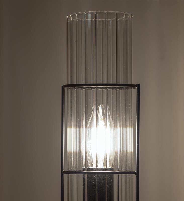Lampa stołowa z przezroczystym, pionowo żebrowanym kloszem, przez który widoczna jest żarówka emitująca jasne światło.