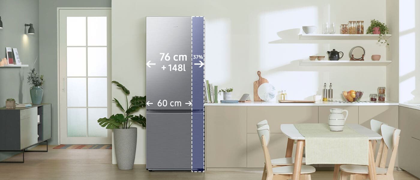 W kuchni znajduje się lodówka w kolorze szczotkowanej stali nierdzewnej z oznaczeniami \'76 cm + 148l\', \'60 cm\' i \'37%\'. W tle widać jasne szafki, stół z krzesłami oraz półki z naczyniami.