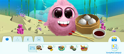 Różowa, futrzasta postać z dużymi oczami i szerokim uśmiechem znajduje się obok koszyka z pierożkami i miseczki z sosem. W tle widać podwodny krajobraz z roślinami i skałami.