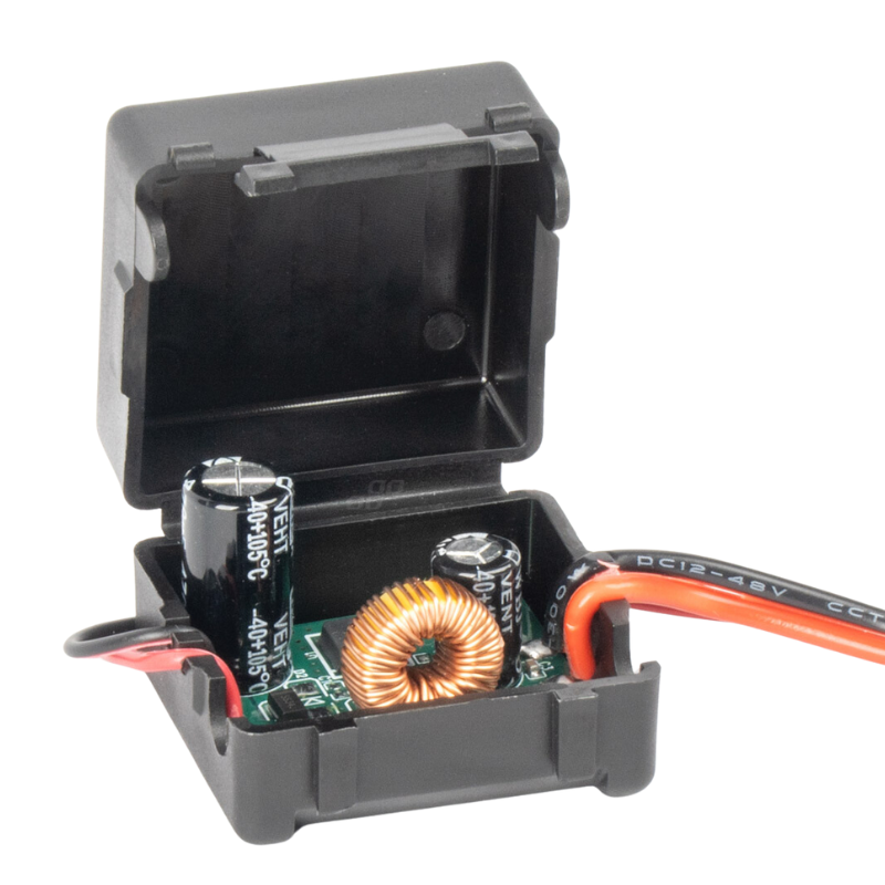 Otwarty czarny plastikowy pojemnik z widocznymi elementami elektronicznymi, w tym cewką i kondensatorami, oraz przewodami z oznaczeniem \'DC12-48V\'.