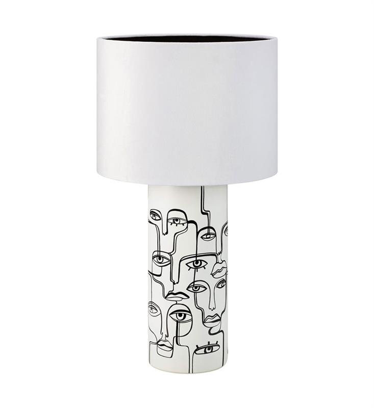 Lampa stołowa z białym abażurem i podstawą ozdobioną czarnymi liniami tworzącymi abstrakcyjne twarze.