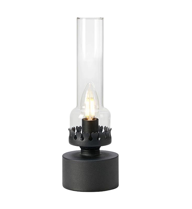 Na obrazie widoczna jest lampa stołowa z przezroczystym szklanym kloszem i czarną podstawą. Wewnątrz klosza znajduje się żarówka w kształcie świecy.