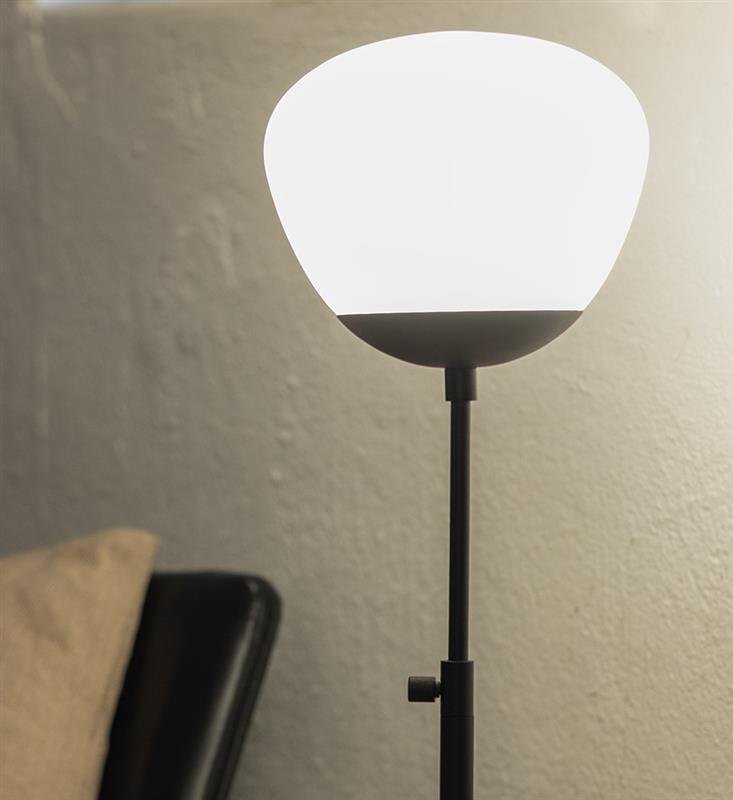 Lampa stołowa z białym kloszem na czarnym stojaku, ustawiona na tle jasnej ściany.