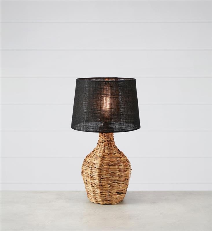 Lampa stołowa z plecioną podstawą i czarnym abażurem, ustawiona na jasnym tle z poziomymi liniami.