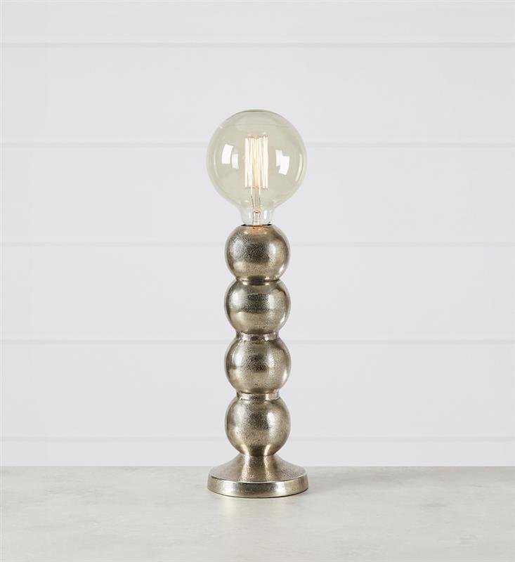 Lampa stołowa z metalową podstawą składającą się z czterech kulistych segmentów i przezroczystą żarówką na górze, ustawiona na jasnym tle.