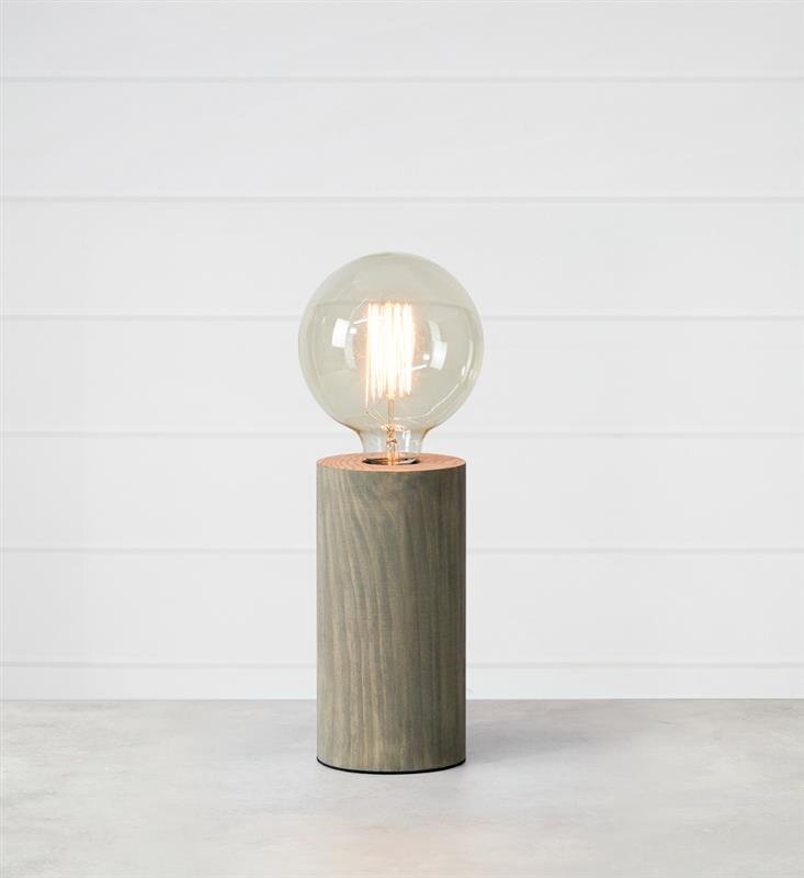 Lampa stołowa z przezroczystą żarówką na cylindrycznej podstawie z drewna, ustawiona na jasnym tle.