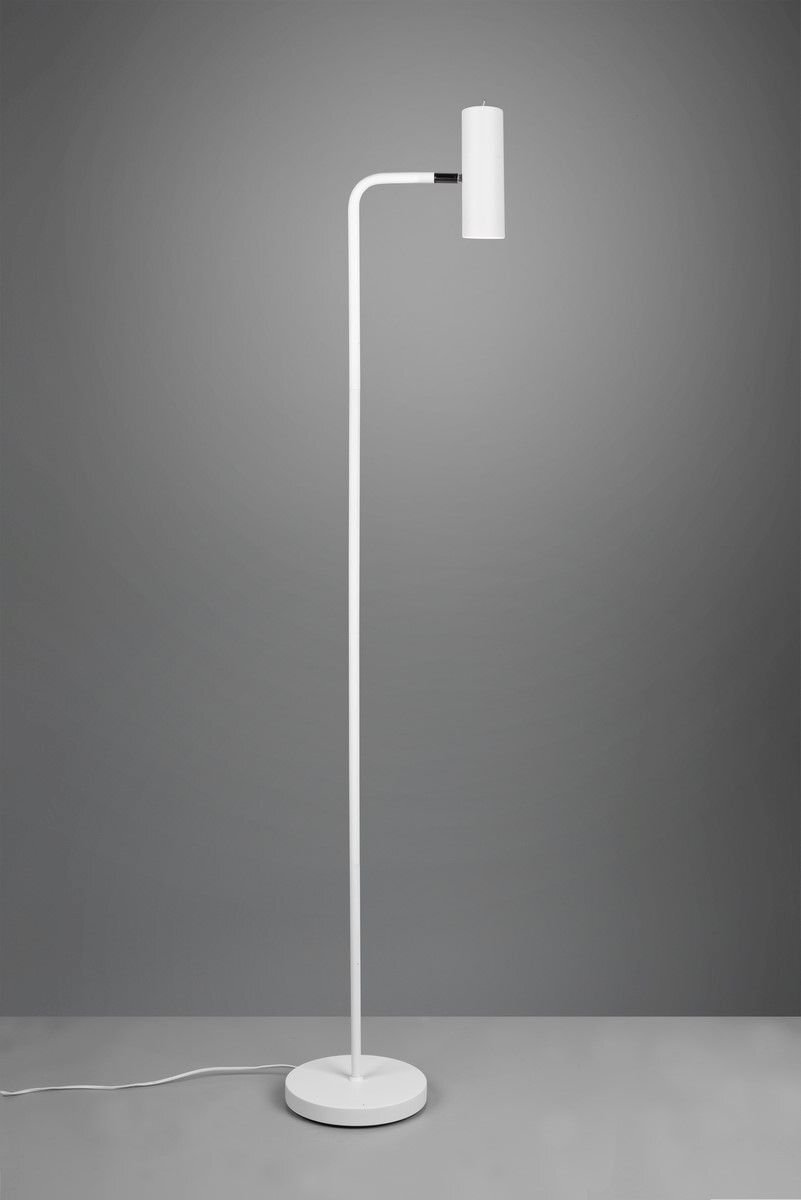 Lampa podłogowa o nowoczesnym designie z białym, smukłym korpusem i cylindrycznym kloszem, stojąca na okrągłej podstawie na tle szarej ściany.