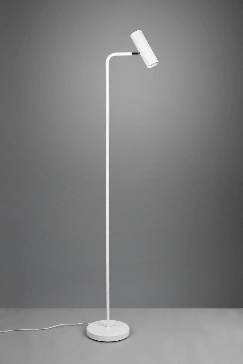 Lampa podłogowa o nowoczesnym designie z białym, smukłym korpusem i cylindrycznym kloszem, stojąca na okrągłej podstawie na tle szarej ściany.