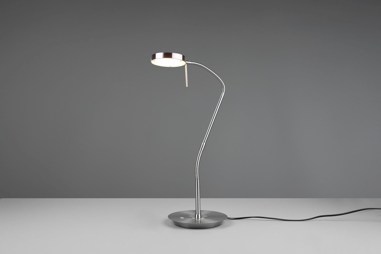 Lampa biurkowa LED Trio NEMIO DL107523310 12W o nowoczesnym designie, stojąca na szarej powierzchni z widocznym kablem zasilającym.