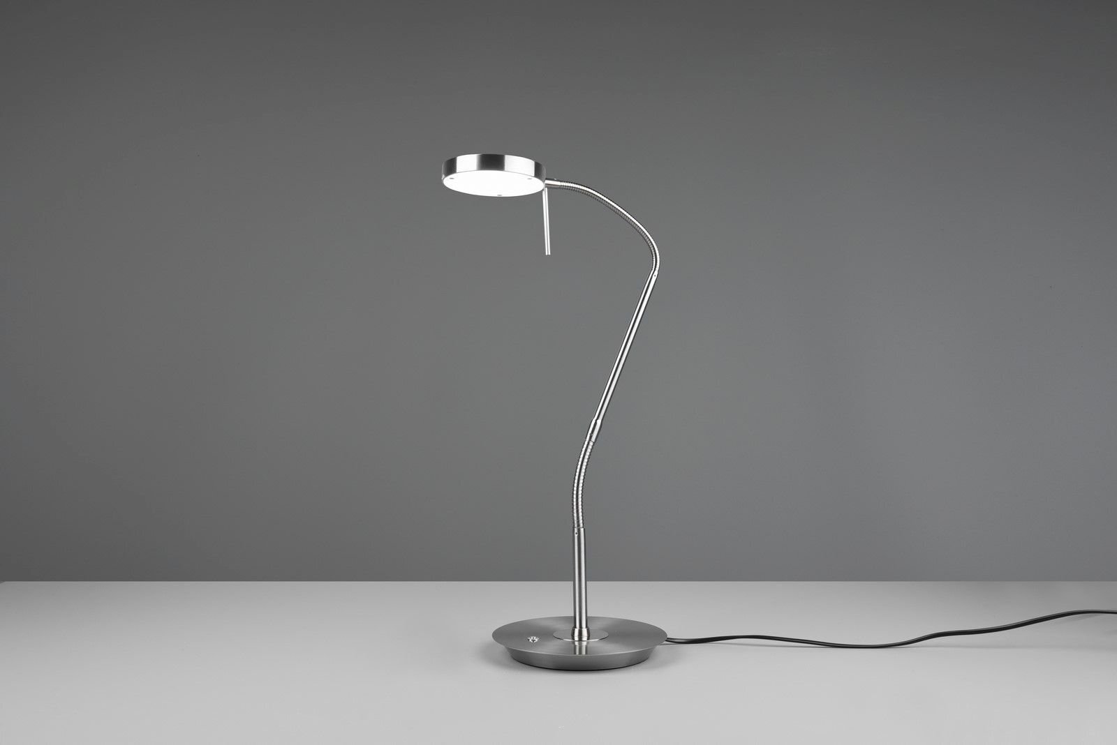Lampa biurkowa LED Trio NEMIO DL107523310 12W o nowoczesnym designie, stojąca na szarej powierzchni z widocznym kablem zasilającym.