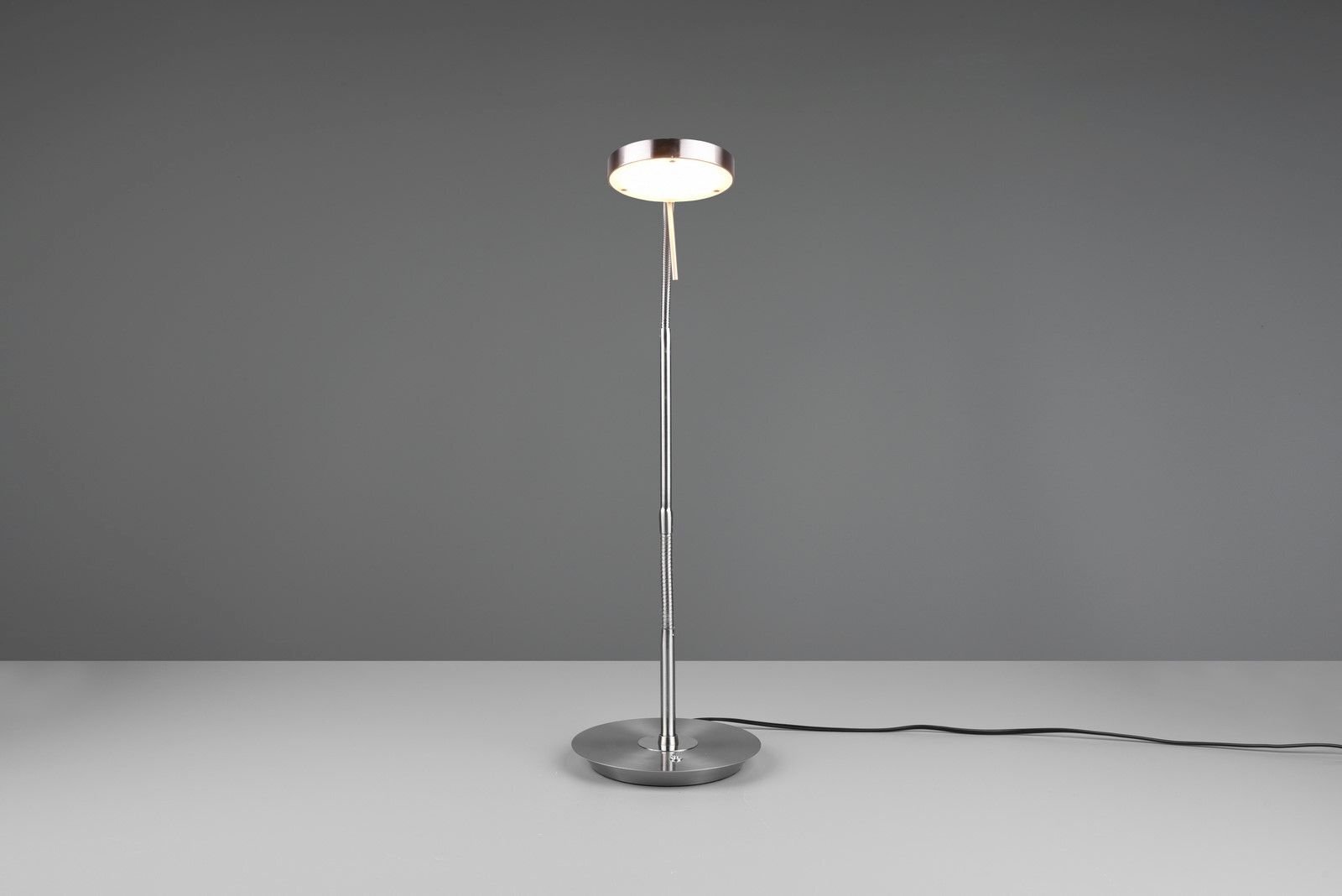 Lampa biurkowa LED Trio NEMIO DL107523310 12W o nowoczesnym designie, stojąca na szarej powierzchni z widocznym kablem zasilającym.
