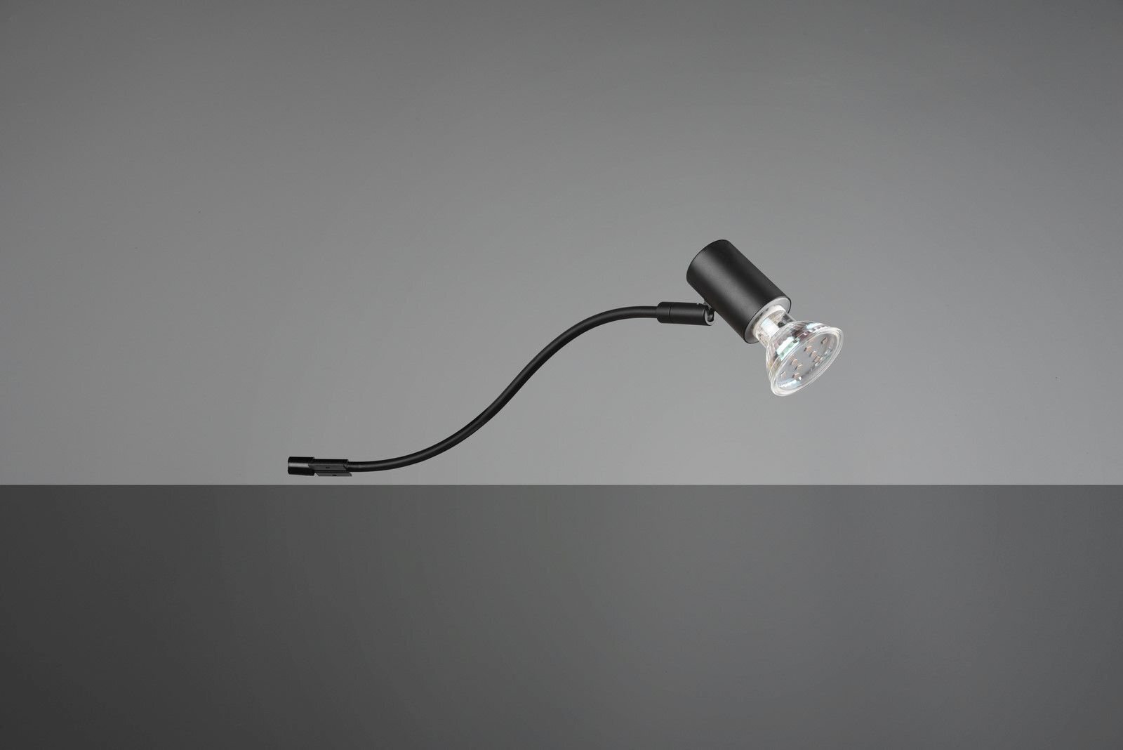 Czarna lampa z elastycznym ramieniem i przezroczystym kloszem na szarym tle.