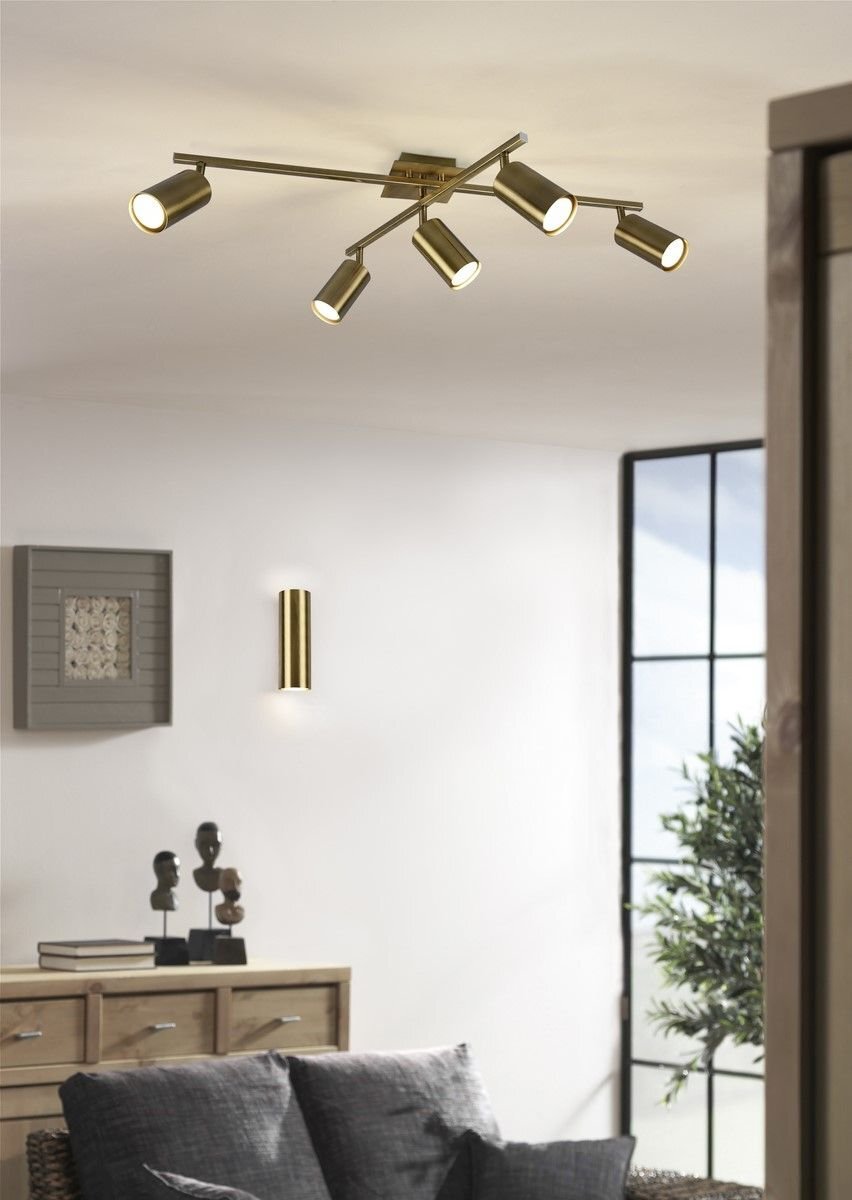 Na zdjęciu znajduje się nowoczesna lampa ścienna VANTOS Trio DL204212400 zamontowana na ścianie w elegancko urządzonym wnętrzu z drewnianymi meblami i dekoracjami.