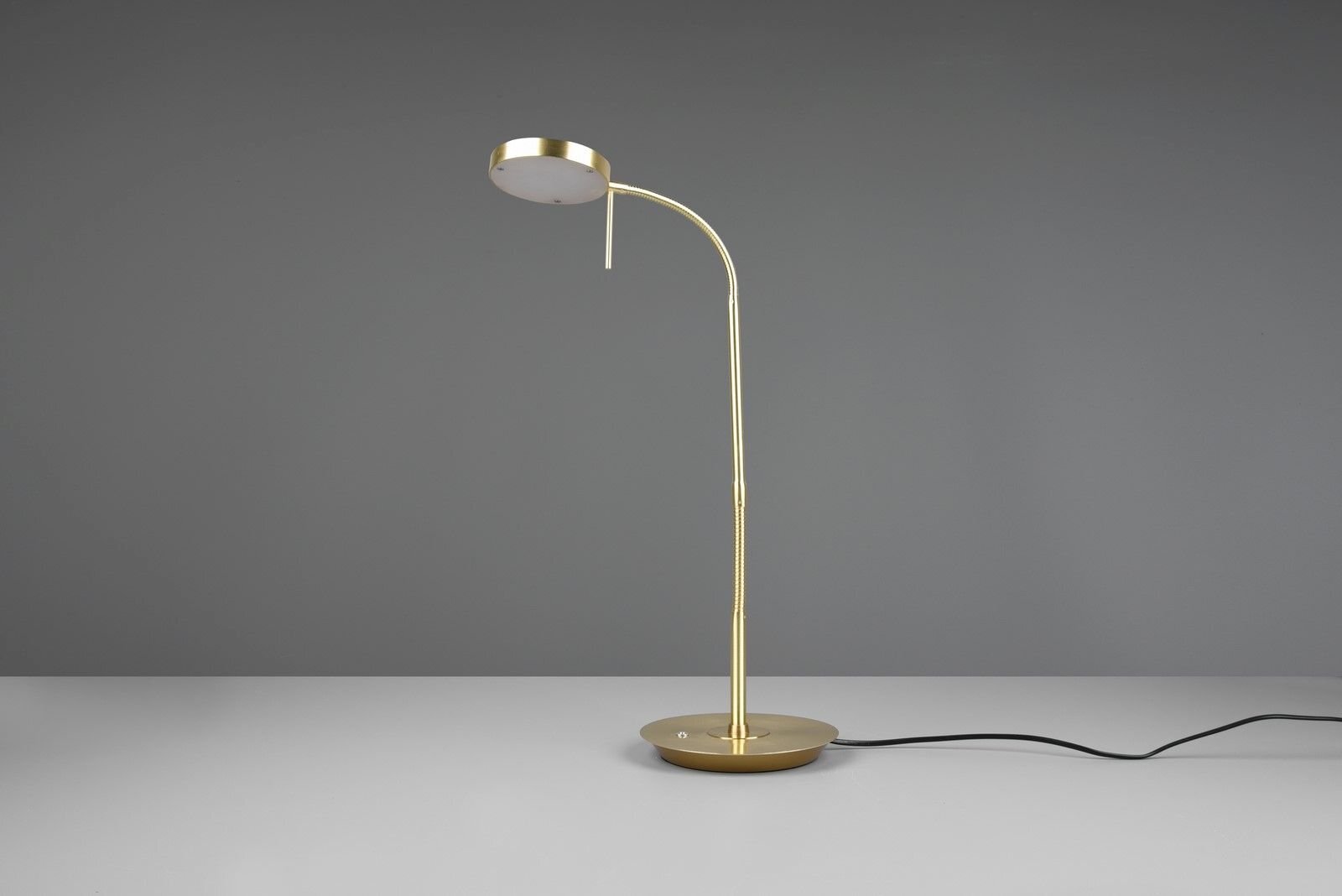 Złota lampa biurkowa LED z okrągłym kloszem na szarej powierzchni, z widocznym czarnym przewodem zasilającym.