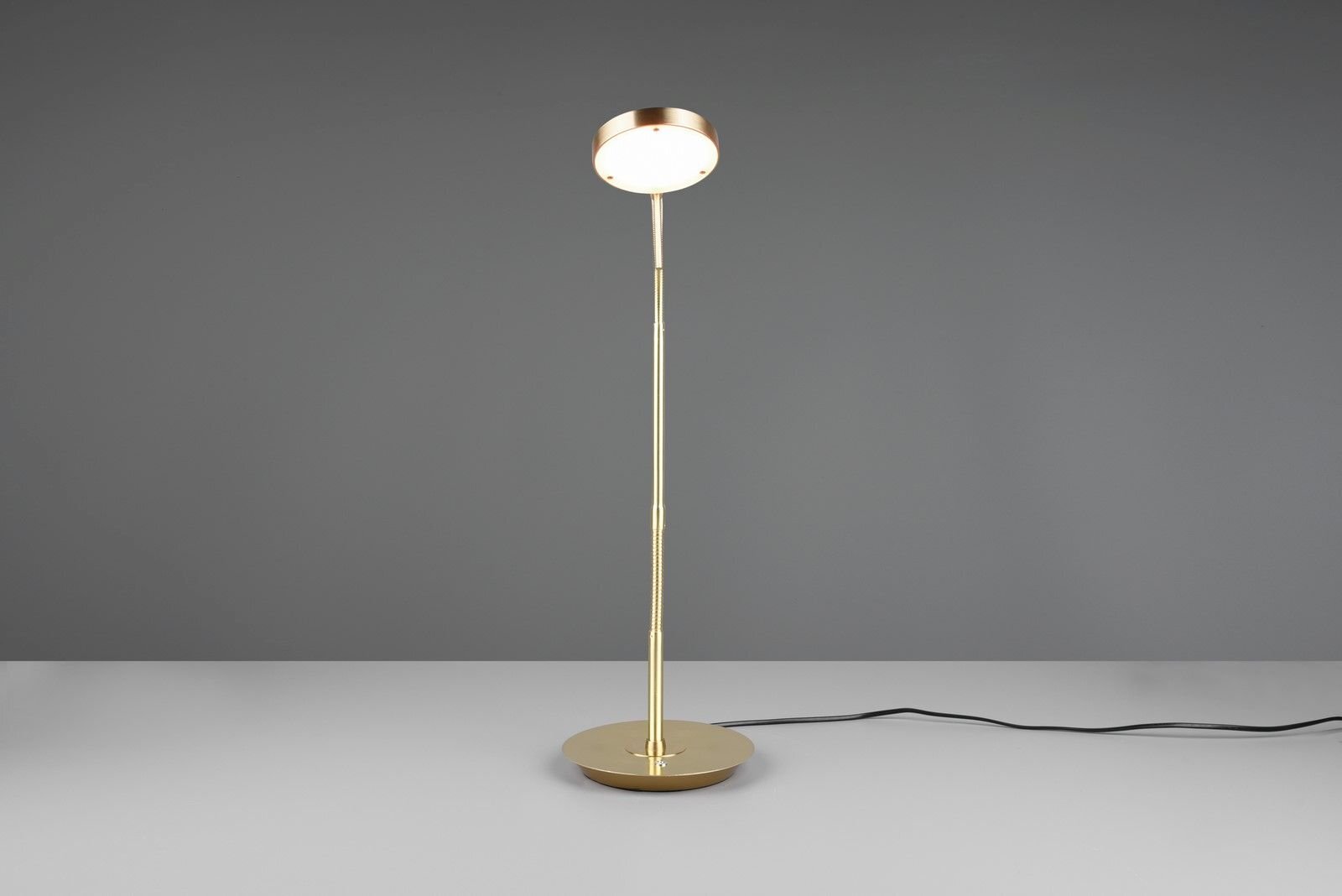 Złota lampa biurkowa LED z okrągłym kloszem na szarej powierzchni, z widocznym czarnym przewodem zasilającym.